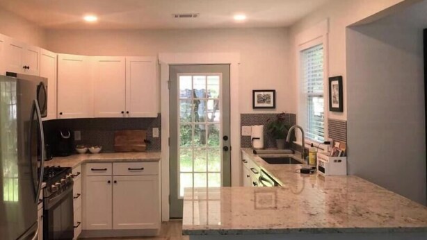 A modern kitchen with white cabinets, stainless steel appliances, and a marble countertop. - Arthouse, freshly renovated 2 bedroom residential (North Charleston)