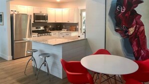 A modern kitchen with a central island, stainless steel appliances, and red bar stools. - Arthouse, freshly renovated 2 bedroom residential (North Charleston)
