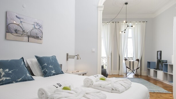 Ein Hotelzimmer mit Bett, einem Fahrradbild an der Wand, einem Fernseher und einem Balkon mit Vorhängen.