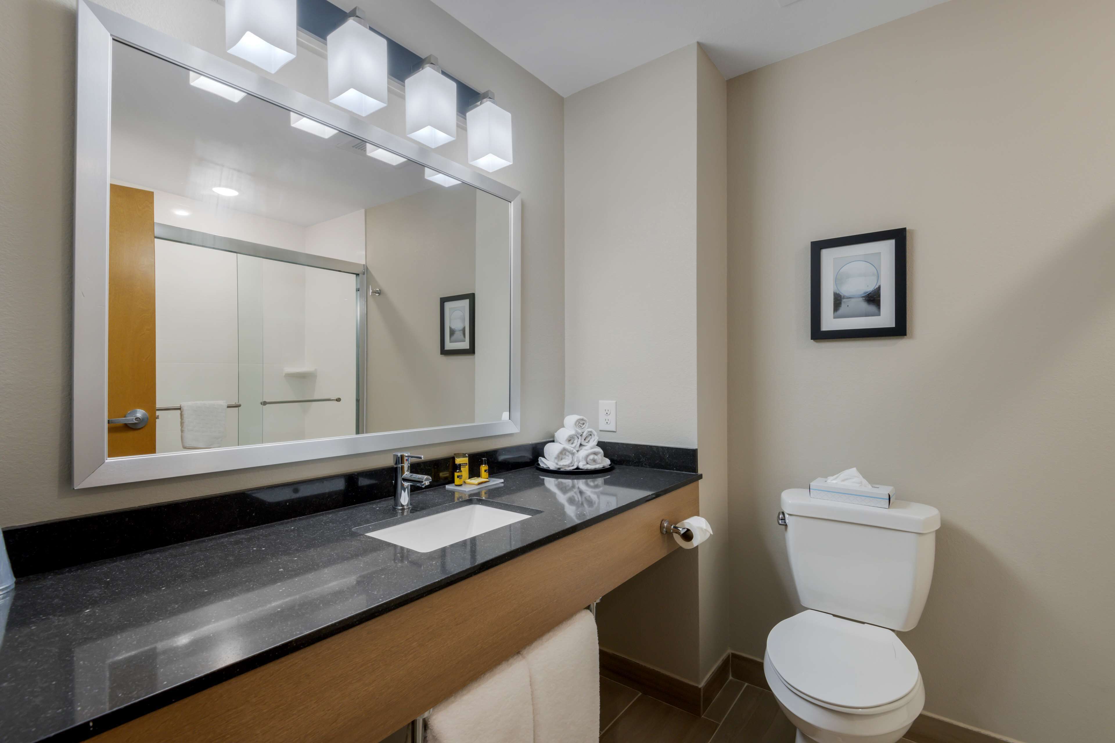 Une salle de bain moderne avec un grand miroir, un lavabo et des toilettes.