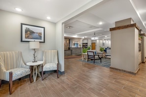 A hotel lobby with striped chairs, a small table, a framed picture on the wall, and a kitchen area in the background. - Best Western Plus Rumford Falls (Rumford)