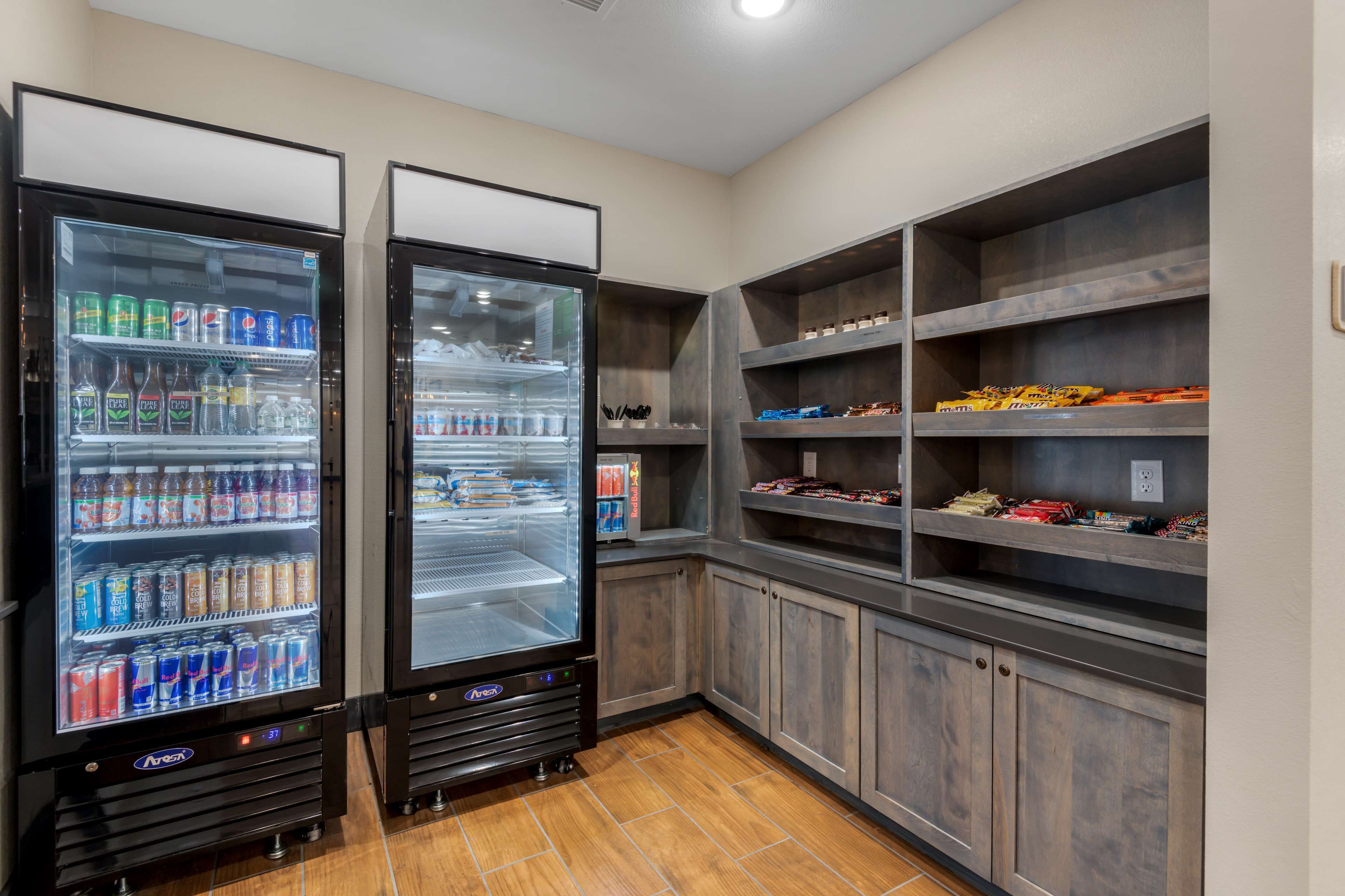 Two beverage vending machines in a room with wooden cabinets and shelves.