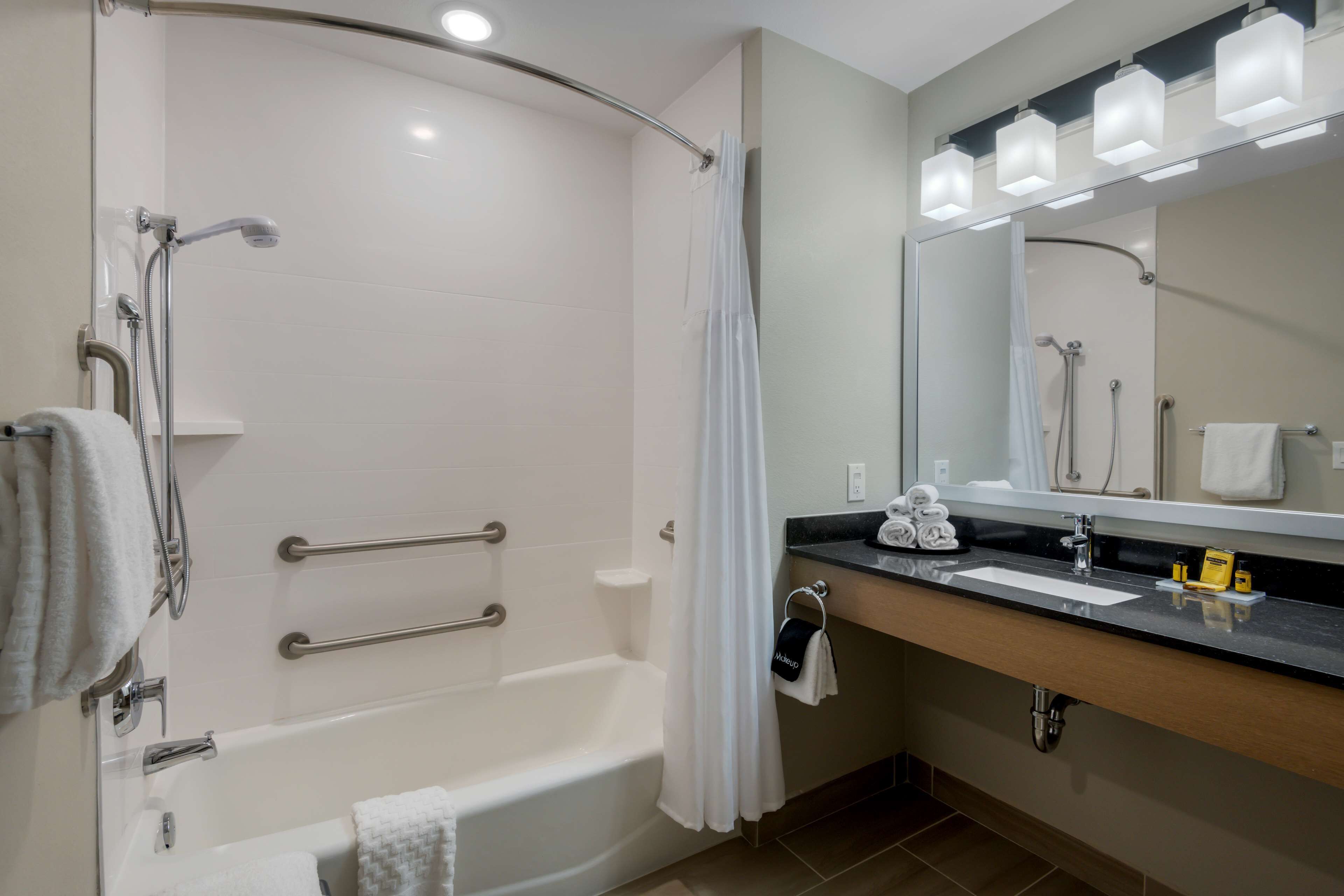A modern bathroom with a bathtub, shower, and vanity with a mirror.