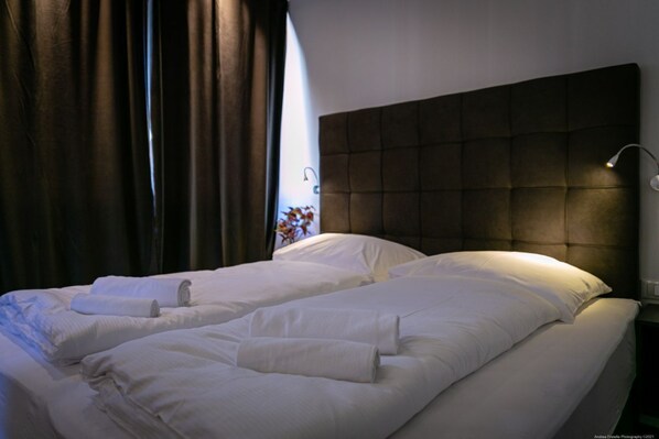 A neatly made bed with white linens and a headboard with a light fixture.