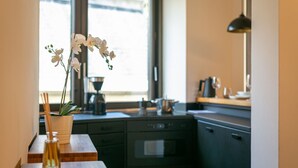 Eine Küche mit einem Holztisch, einer Vase mit weißen Blumen und einem Fenster mit Tageslicht.