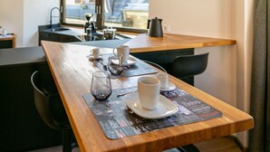 Ein Holztisch mit Untertasse, zwei weiße Tassen, ein Glas und ein Teekessel.