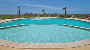 A swimming pool with multiple lanes, surrounded by palm trees and lounge chairs. - PATHWAY TO THE SEA, 3RD FLOOR PENTHOUSE! HEATED POOL AND STEPS FROM OCEAN! (Corpus Christi)