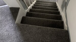 A staircase with carpeted steps leading to a landing with a white door and a small framed picture. - Timbered House (herefordshire)