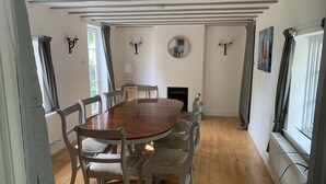 A dining room with a wooden table and six chairs, a fireplace, and a large mirror on the wall. - Timbered House (herefordshire)