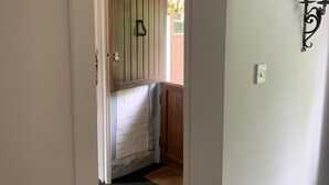 A narrow hallway with a wooden door leading to a room with a bed and a window. - Timbered House (herefordshire)