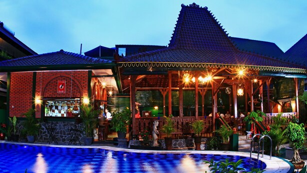 Un hotel con piscina, zona de estar al aire libre y un letrero de Coca-Cola.