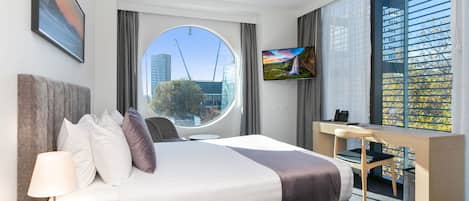 Een moderne hotelkamer met een groot bed, een bureau en een televisie.