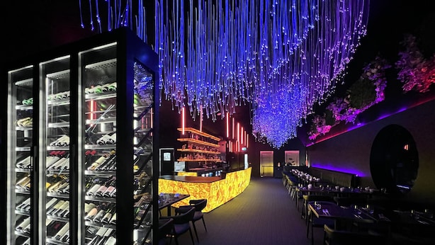 A bar area with a neon-lit ceiling, a counter with a marble-like front, and shelves with bottles. - Christchurch City Hotel (Christchurch)