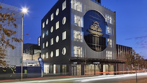 A modern hotel with a distinctive circular logo, multiple windows, and a prominent entrance. - Christchurch City Hotel (Christchurch)
