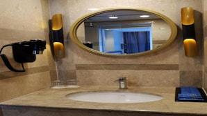 A bathroom with a round mirror, a sink, and two wall-mounted soap dispensers. - Arthama Hotel Tanah Abang Jakarta (Jakarta)