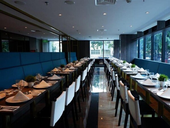 A modern restaurant with long tables and blue cushioned seating. - Arthama Hotel Tanah Abang Jakarta (Jakarta)