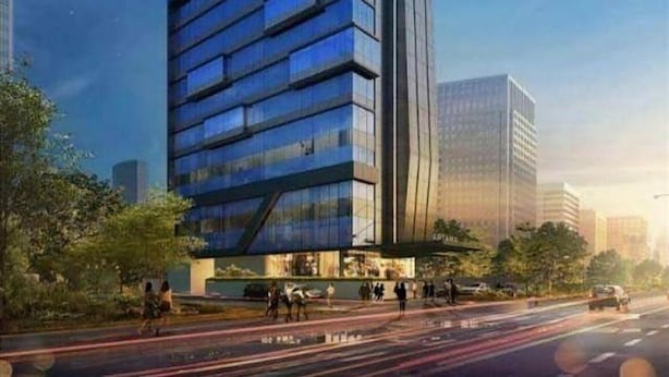 A modern high-rise building with a glass facade, surrounded by trees and a busy street. - Arthama Hotel Tanah Abang Jakarta (Jakarta)