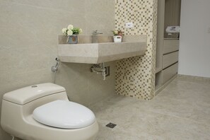 A bathroom with a toilet, sink, and shower.