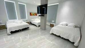 Quarto de hotel moderno com duas camas, televisão de tela plana e uma janela grande.