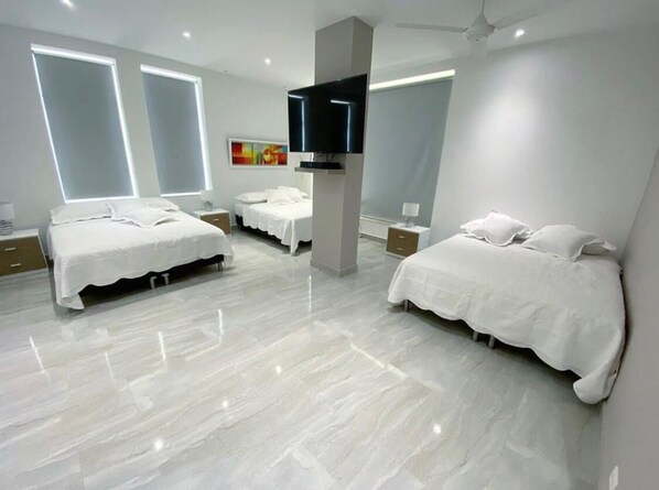 A modern hotel room with two beds, a flat-screen TV, and a large window.