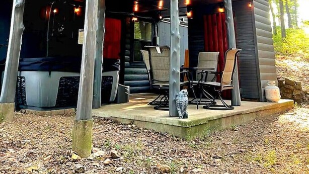 A two-story cabin with a balcony, outdoor seating, and a view of the surrounding trees. - Aunt B`s Cabin  W/  Hot Tub!  Near Table Rock Lake (Lampe)