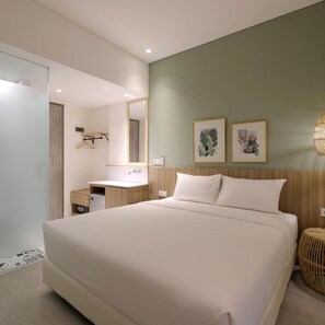 Ein modernes Hotelzimmer mit einem großen Bett, einem Holzkopfteil, einem kleinen Nachttisch, einem Spiegel und zwei gerahmten Bildern an der Wand.