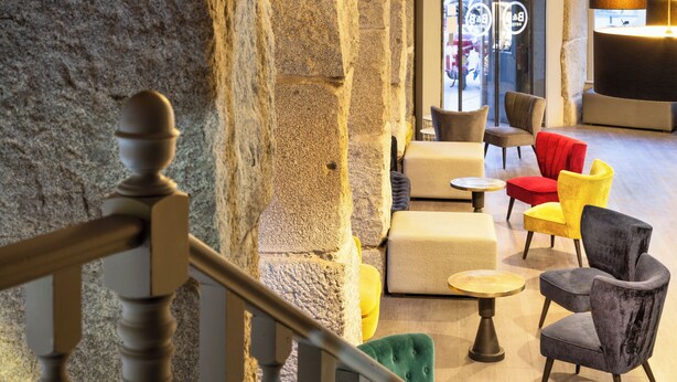 A modern interior with stone walls, a staircase, and a seating area with various chairs and tables. - B&B Hotel Madrid Centro Plaza Mayor (Madrid)