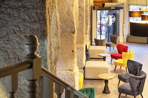 A modern interior with stone walls, a staircase, and a seating area with various chairs and tables.