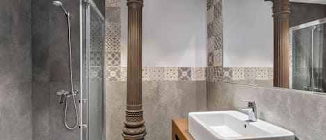 Une salle de bain avec une douche, un lavabo et des colonnes décoratives.