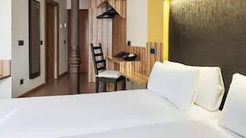 A hotel room with a large bed, a wooden headboard, a small desk with a chair, and a mirror.