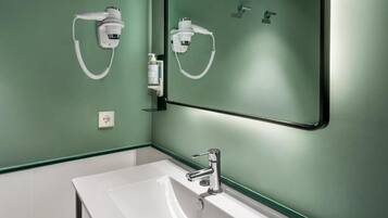 Un baño con un lavamanos blanco, un espejo y dos cabezales de ducha manuales blancos montados en la pared.