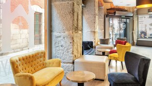 A modern interior with a yellow sofa, a dark armchair, and a round wooden table. - B&B Hotel Madrid Centro Plaza Mayor (Madrid)