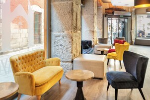 A modern interior with a yellow sofa, a dark armchair, and a round wooden table.