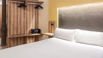 A hotel room with a large bed, wooden headboard, and a small bedside table with a radio.