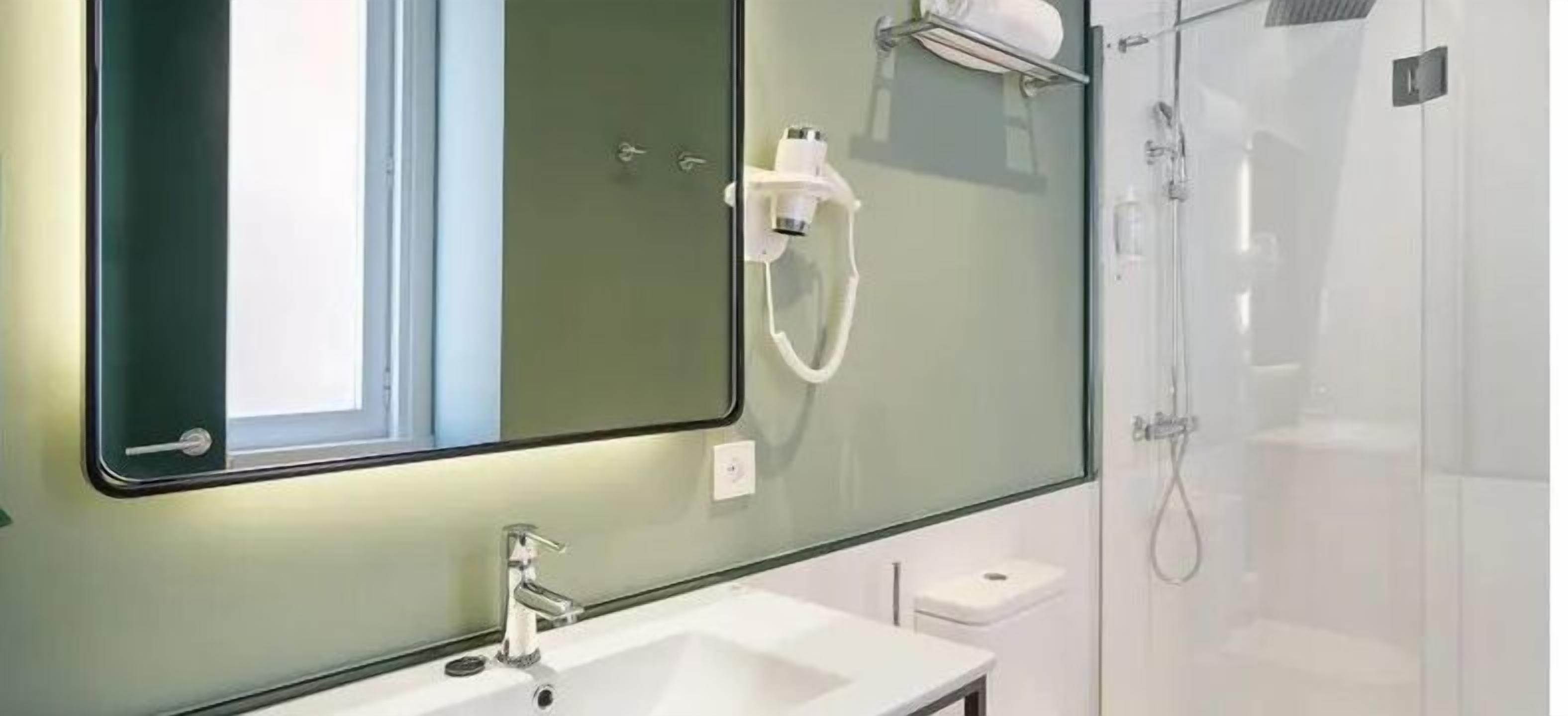 Une salle de bain moderne avec un grand miroir, un lavabo et une douche.