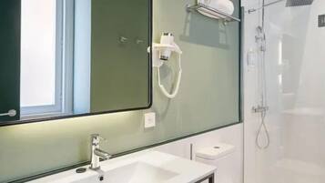 Un baño moderno con un espejo grande, un lavamanos y una ducha.