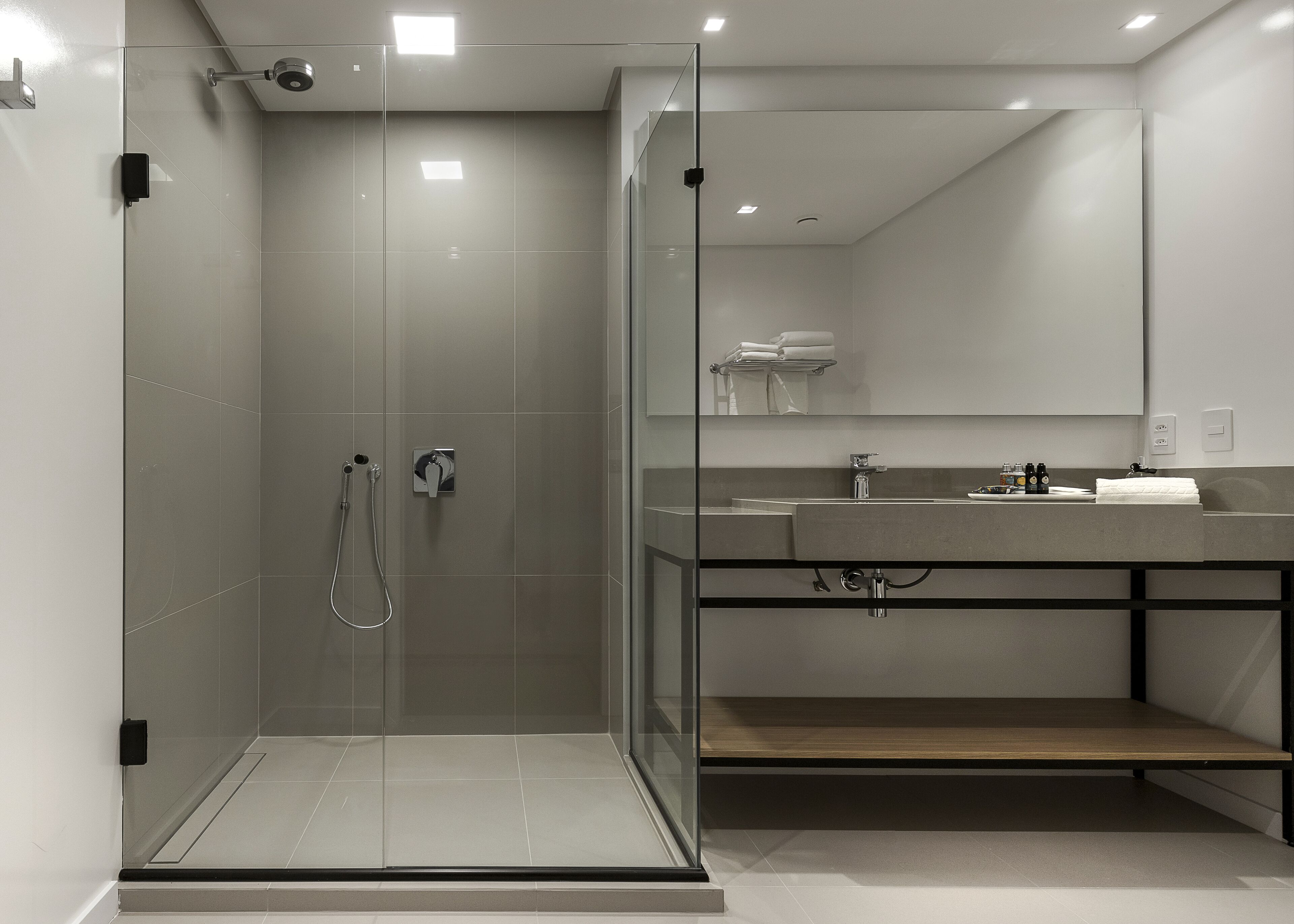 A modern bathroom with a glass-enclosed shower, a vanity with a sink, and a mirror above the sink.