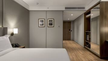 A modern hotel room with a large bed, bedside table with a lamp, a phone, and two framed pictures on the wall.