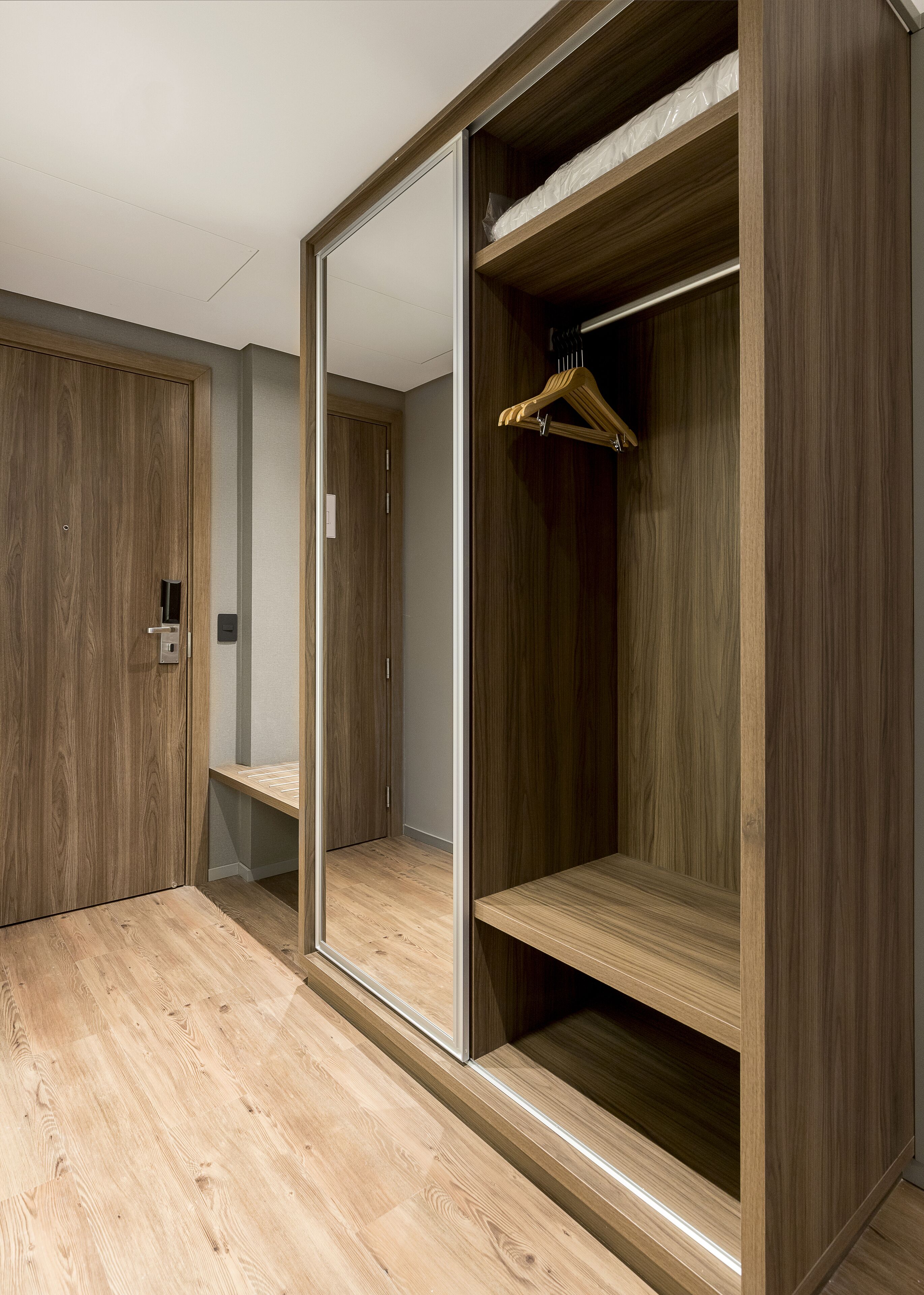 A walk-in closet with wooden doors, a mirror, and a hanging rod.