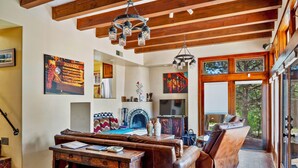 Una sala de estar acogedora con chimenea, sofá de cuero, mesa de madera y obras de arte en las paredes.