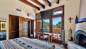Un dormitorio con una cama grande, televisión, chimenea y balcón con vistas.