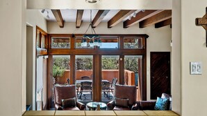 Una habitación amplia con un gran ventanal, vigas de madera y un ventilador de techo.
