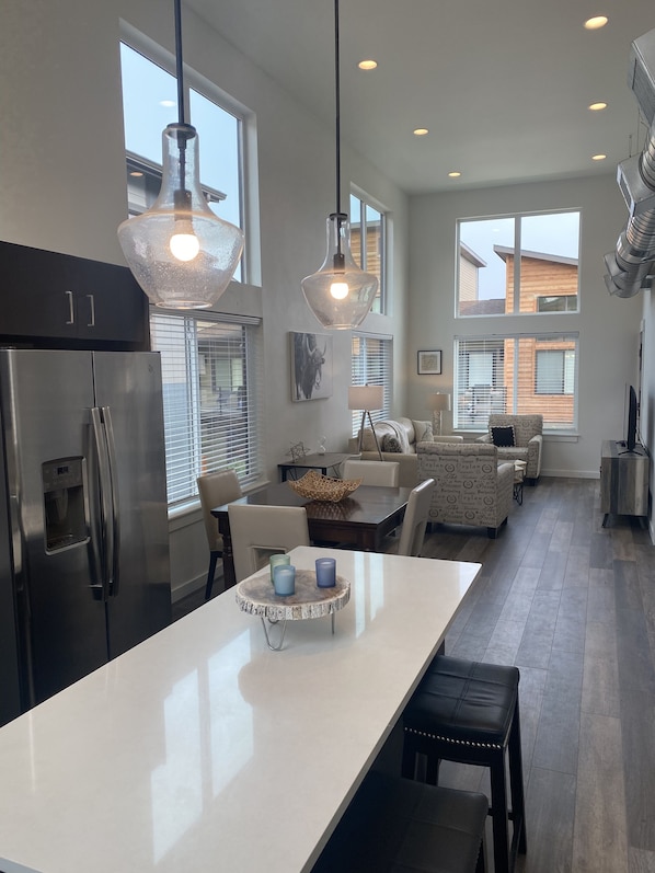 A modern kitchen with a large island, stainless steel appliances, and pendant lighting.