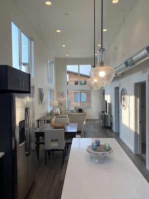 A modern kitchen with a central island, built-in appliances, and a dining area with a view to the living room.