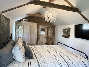 Une chambre à coucher avec un grand lit, un lustre, une armoire et un téléviseur.