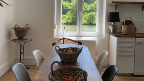 A dining area with a wooden table, wicker baskets, and a view of a forest through a window. - Country house for 15 people, waterfront in the Ardennes nature park (Revin)