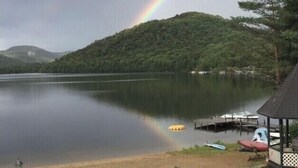 Vista de un lago con arcoíris, barcos amarrados y un pabellón.