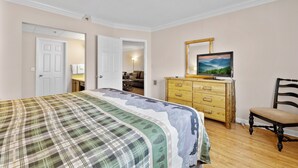 A bedroom with a bed, dresser, chair, and a painting on the wall. - 2 BR Condo on the River! Walk to the Island (Pigeon Forge)