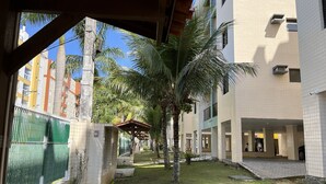 A courtyard with a covered seating area, palm trees, and a fenced garden.