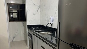 A modern kitchen with a stainless steel refrigerator, a black countertop, and marble backsplash.